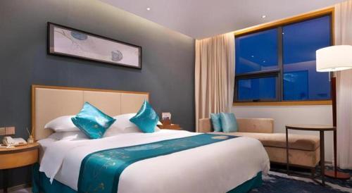 a hotel room with a large bed with blue pillows at Fliport Garden Hotel Nanjing in Nanjing