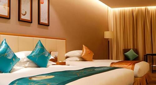 a hotel room with two beds with blue pillows at Fliport Garden Hotel Nanjing in Nanjing