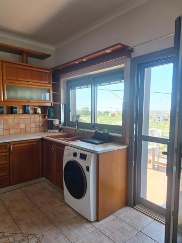 a kitchen with a washing machine and a window at Solena in Tsikalariá
