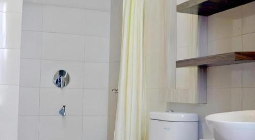 a white bathroom with a toilet and a sink at Grant Hotel Subang in Bandung