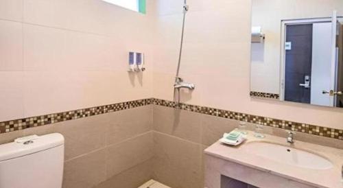 a bathroom with a toilet and a sink and a mirror at Lotus Hotel Subang in Bandung