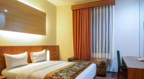 a hotel room with a bed and a desk and a window at Lotus Hotel Subang in Bandung