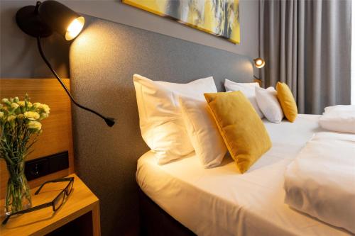 a bedroom with a bed with white pillows and a vase of flowers at Best Western Parkhotel Hagenberg in Hagenberg im Mühlkreis