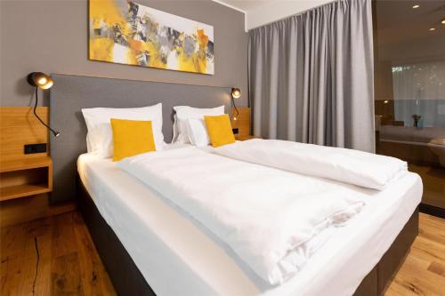 a bedroom with a large white bed with yellow pillows at Best Western Parkhotel Hagenberg in Hagenberg im Mühlkreis