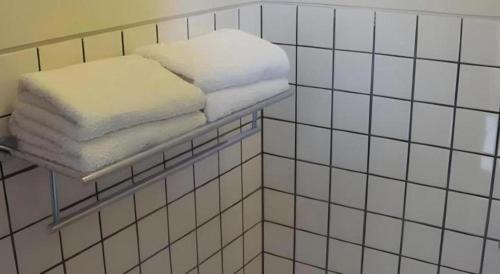 a shelf with towels on it in a bathroom at d'Emmerick Salib Putih Hotel Salatiga in Salatiga
