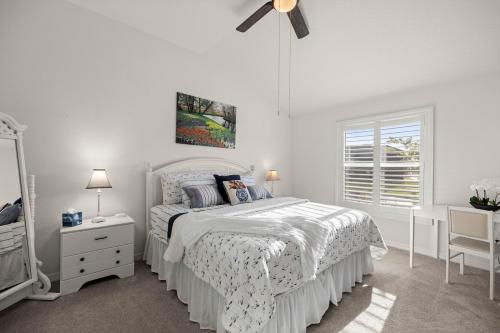 Un dormitorio blanco con una cama y un espejo. en Cozy 2BR in The Villages With BBQ and 4 Seaters Golfcart King Bed, en Wildwood