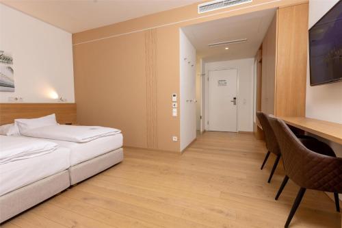 a bedroom with a bed and a desk with chairs at Best Western Hotel Spinnerei Linz in Linz