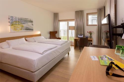 a hotel room with a bed and a desk and a table at Best Western Hotel Spinnerei Linz in Linz