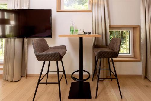 a living room with two bar stools and a tv at Best Western Hotel Spinnerei Linz in Linz
