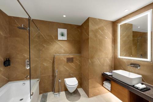 a bathroom with a toilet and a sink and a shower at Ramada Encore by Wyndham Viramgam in Viramgām