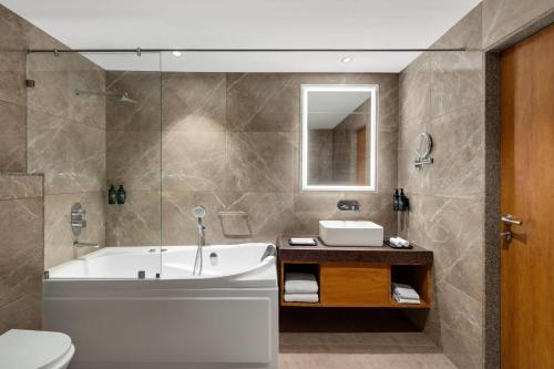 a bathroom with a tub and a sink and a toilet at Ramada Encore by Wyndham Viramgam in Viramgām