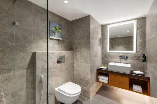 a bathroom with a toilet and a glass shower at Ramada Encore by Wyndham Viramgam in Viramgām