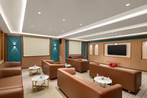 a waiting room with brown chairs and a flat screen tv at Ramada Encore by Wyndham Viramgam in Viramgām