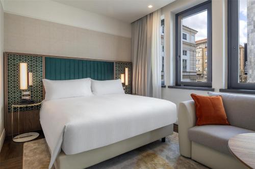 a bedroom with a bed and a chair and a window at Hilton Turin Centre in Turin