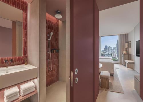 a bathroom with a sink and a shower and a bed at Kromo Bangkok, Curio Collection By Hilton in Bangkok