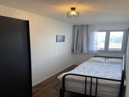 a small bedroom with a bed and a window at Charming apartment with hill view in Veysonnaz