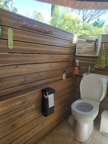 La salle de bains est pourvue de toilettes et d'un mur en bois. dans l'établissement Haut de Villa VERDUREVE location de vacances, à Fréjus
