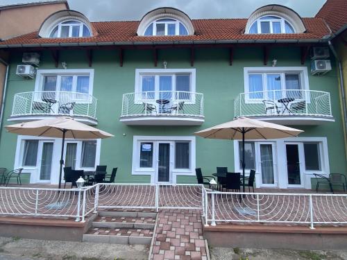 a building with chairs and umbrellas in front of it at Lillybeth Lakeside in Keszthely