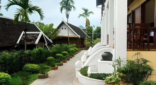 a row of white benches in a courtyard with plants at The View Pavilion Hotel in Luang Prabang