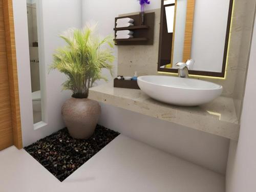a bathroom with a sink and a vase with a plant at De Lemon Gatsu Hotel in Ubud