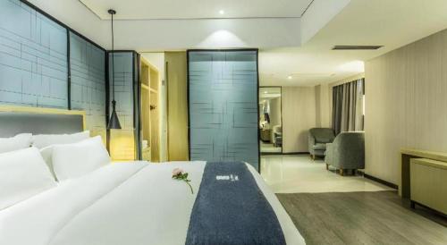 a bedroom with a large white bed with a flower on it at Echarm Hotel Beihai Railway Station in Beihai