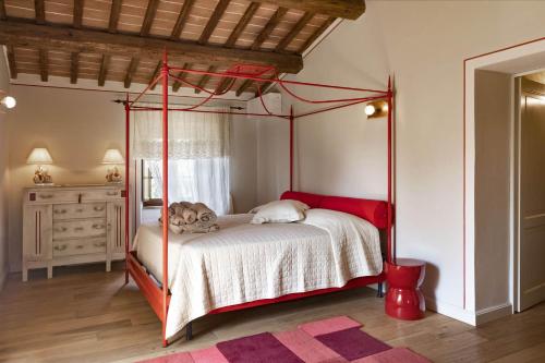 a bedroom with a four poster bed with a red frame at Villa Pieve San Giovanni in Lustignano