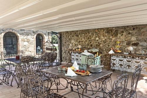 an outdoor patio with tables and chairs and a stone wall at Villa Pieve San Giovanni in Lustignano