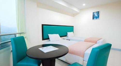 a room with a bed and a table and chairs at Nice Beach Hotel in Rayong