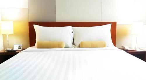 a large white bed with two pillows on it at PARK HOTEL Cawang Jakarta in Jakarta