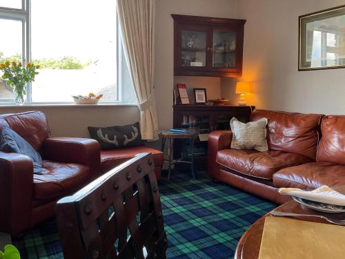 a living room with leather couches and a table at Shambles Cottage in Ambleside