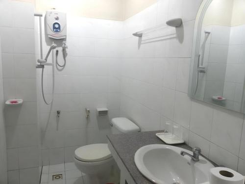 a white bathroom with a toilet and a sink at Sisavath Hotel in Ban Houadông