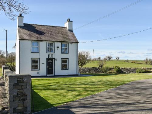 a white house with a grassy yard next to a road at Glanrhyd in Llanrhwydrys