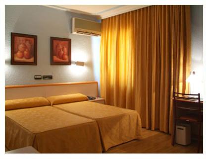 a hotel room with a bed and a window at Hotel Verona in Puertollano