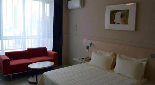 a hotel room with a bed and a red couch at Jinjiang Inn Pingyao Branch in Pingyao