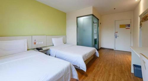 a hotel room with two beds and a glass door at 7 Days Inn Xi'an Railway Station in Xi'an