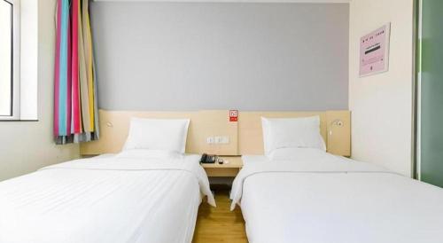 two beds sitting next to each other in a room at 7 Days Inn Hohhot Hailiang Xinhua Square Metro Station in Hohhot