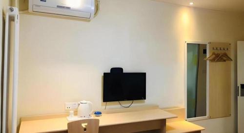 a room with a desk with a tv on the wall at 7 Days Inn Hohhot Hailiang Xinhua Square Metro Station in Hohhot