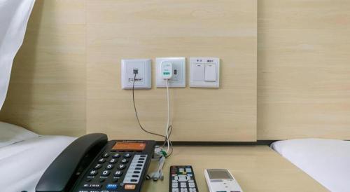 a room with a bed with a remote control on a desk at 7 Days Inn Hohhot Hailiang Xinhua Square Metro Station in Hohhot