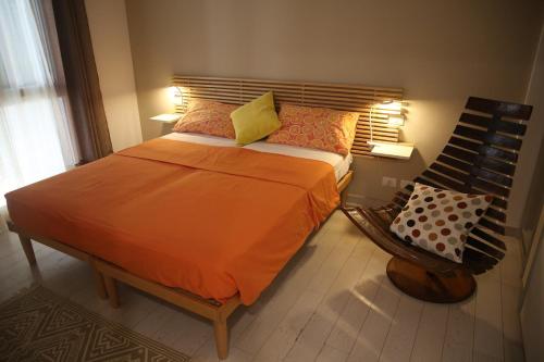 a bedroom with a bed with an orange comforter and a chair at A Casa di Lilly in Albenga