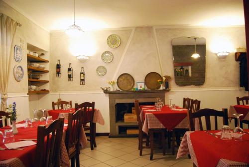 a restaurant with red tables and chairs and a fireplace at Albergo Ristorante La Rocca in Firenzuola