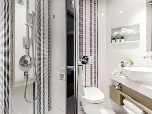 a bathroom with a shower and a toilet and a sink at Elysion Place Hotel Causeway Bay in Hong Kong