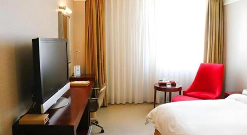 a hotel room with a television and a red chair at Best Western Plus Fuzhou Fortune Hotel in Fuzhou