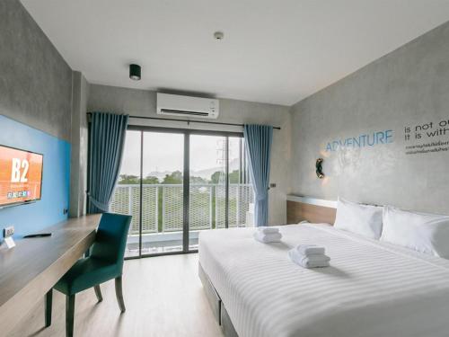 a bedroom with a bed and a desk and a large window at B2 Krabi Premier Hotel in Ao Nang Beach