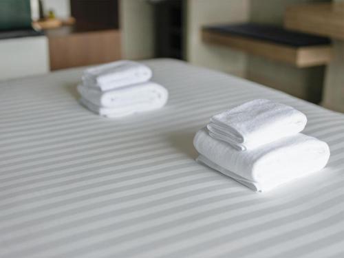 three towels sitting on top of a bed at B2 Krabi Premier Hotel in Ao Nang Beach