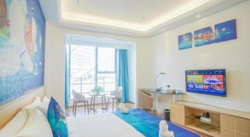 a bedroom with a bed and a table and a television at Beluga Sanya Discovery Ocean World in Shangsimacun