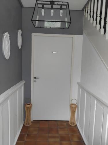 a hallway with a white door and a chandelier at Le Rocher du Samoyède in Dirinon