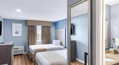 a hotel room with two beds and a mirror at Rodeway Inn & Suites Port Arthur - Groves in Port Arthur