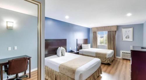 a hotel room with two beds and a mirror at Rodeway Inn & Suites Port Arthur - Groves in Port Arthur
