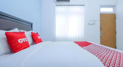 a bedroom with a large bed with red pillows at OYO 1755 De'balcon Accomodation Near Ngurah Rai Airport in Ubud