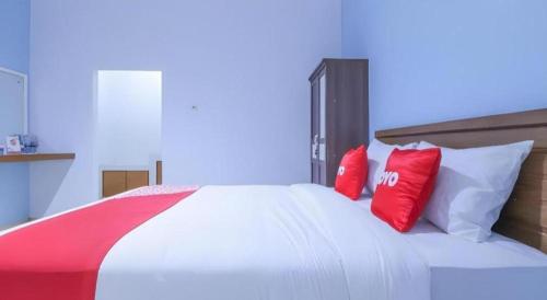 a bed with red and white pillows on it at OYO 1755 De'balcon Accomodation Near Ngurah Rai Airport in Ubud